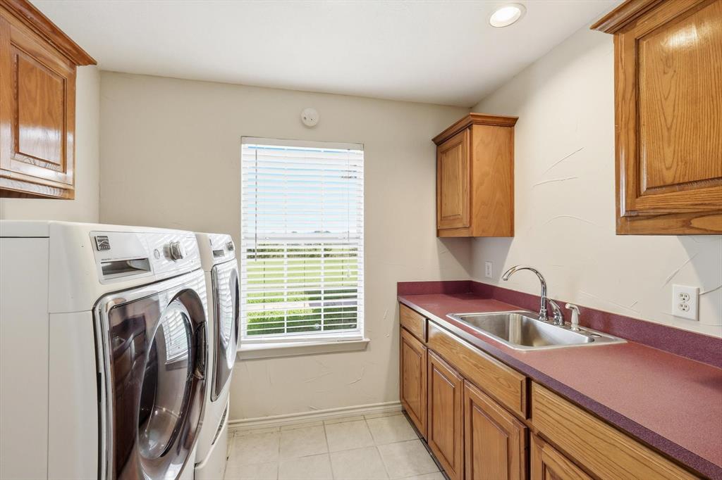 12190 Bell Road Pilot Point, TX 76258 - Photo 19 of 39 Utility room featuring a built-in sink, ample counter space, custom wood cabinetry, and a window for natural light