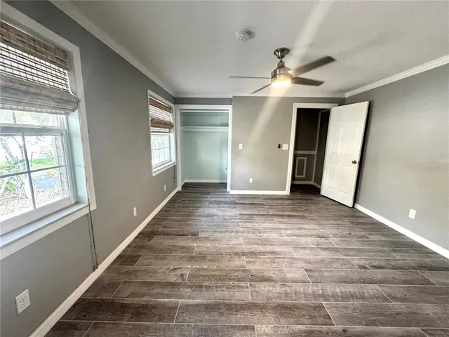a view of an empty room with wooden floor and a window