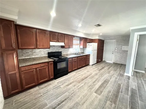 a kitchen with stainless steel appliances granite countertop a refrigerator a sink dishwasher a stove with wooden cabinets and floor