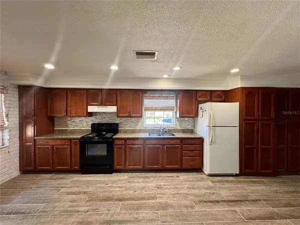 a large kitchen with stainless steel appliances granite countertop a stove and a refrigerator