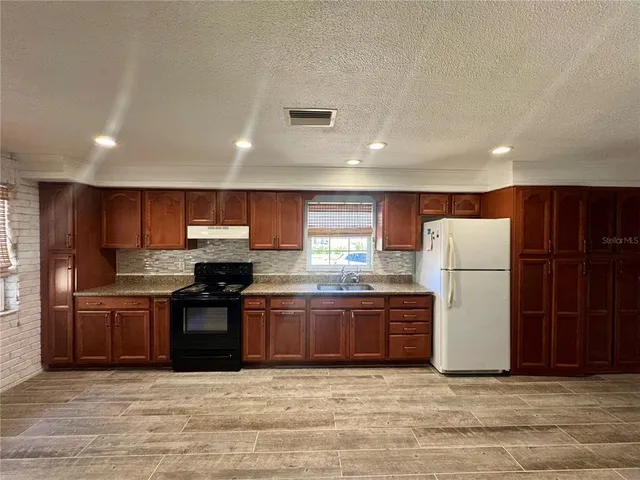 a large kitchen with stainless steel appliances granite countertop a stove and a refrigerator