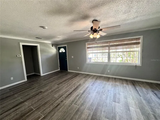 a view of an empty room with wooden floor and a window