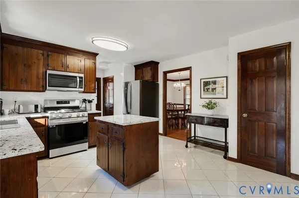 a kitchen with stainless steel appliances granite countertop a stove top oven a sink dishwasher and a refrigerator with wooden cabinets