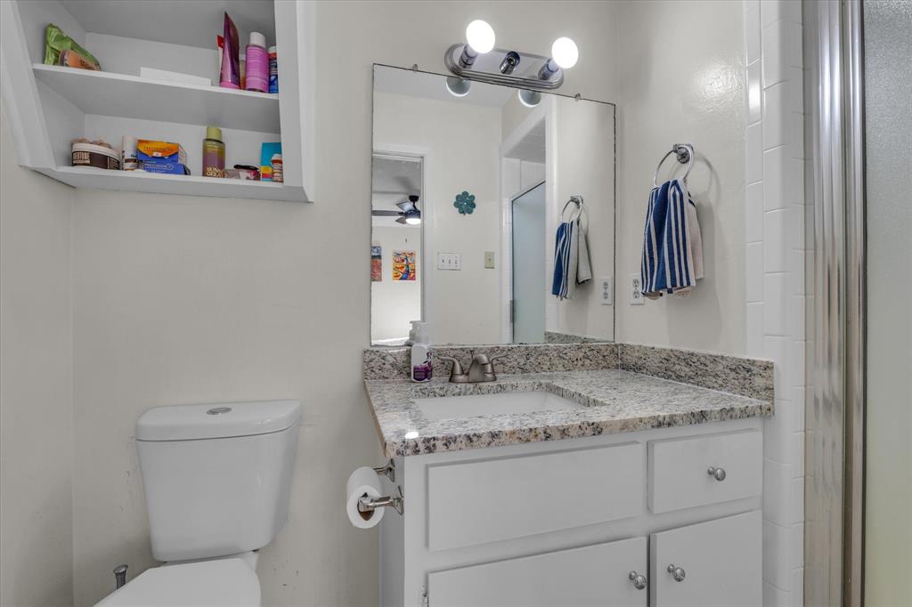 1421 South 12th Street, Unit 103 Waco, TX 76706 - Photo 11 of 17 a bathroom with a granite countertop sink a toilet and a mirror