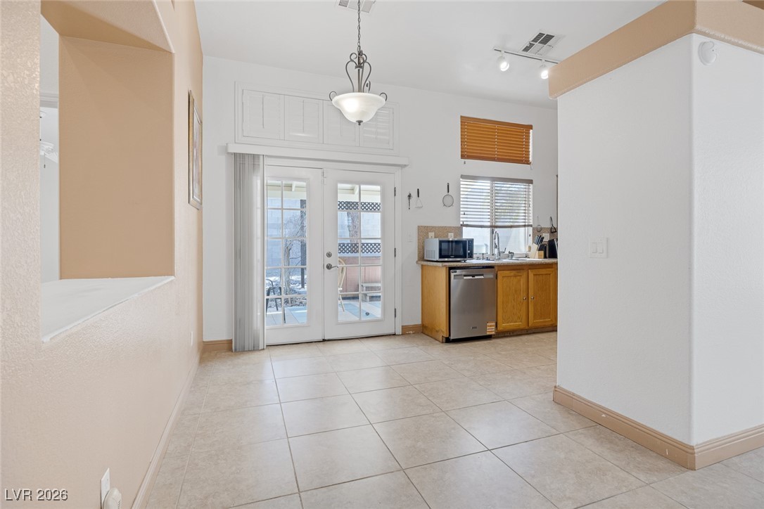 2427 Worchester Road Henderson, NV 89074 - Photo 12 of 35 Kitchen featuring brown cabinets, light tile patterned flooring, pendant lighting, french doors, and dishwasher