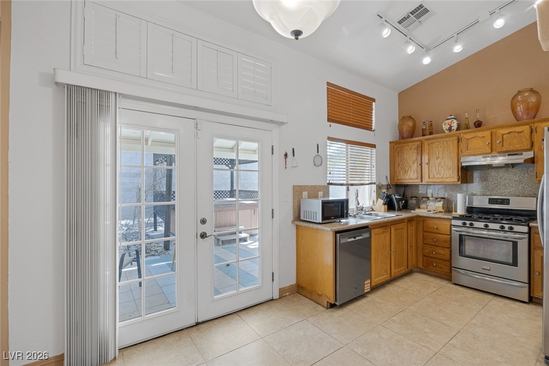 2427 Worchester Road Henderson, NV 89074 - Photo 13 of 35 Kitchen with french doors, stainless steel appliances, light countertops, tasteful backsplash, and light tile patterned flooring
