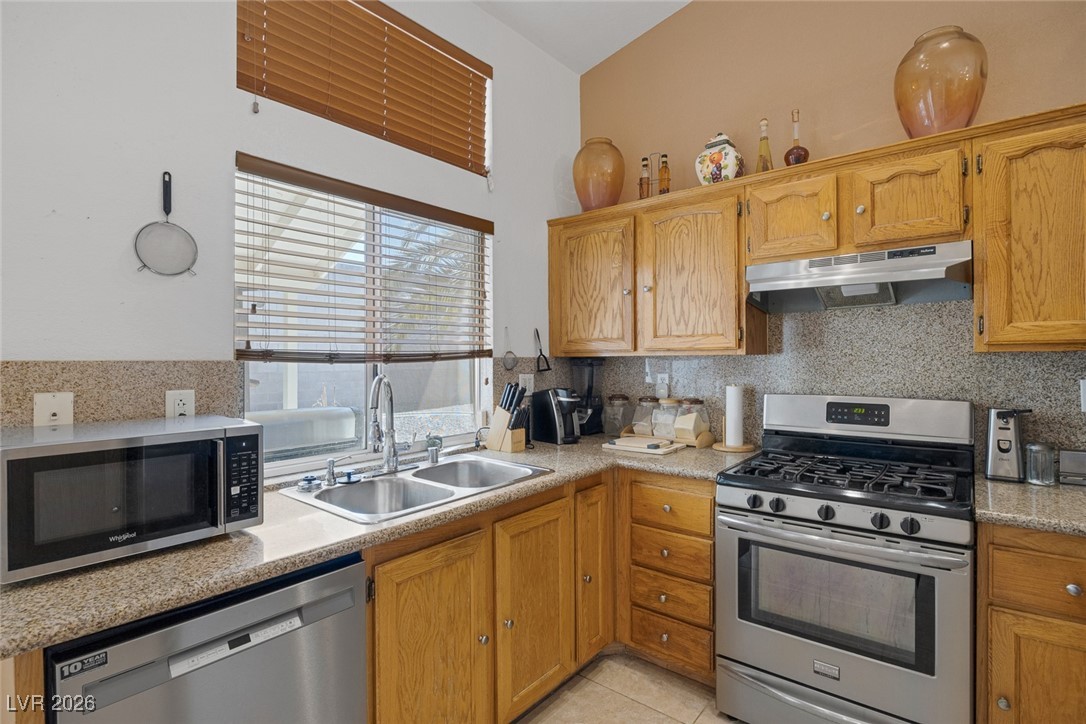 2427 Worchester Road Henderson, NV 89074 - Photo 15 of 35 Kitchen featuring appliances with stainless steel finishes, decorative backsplash, under cabinet range hood, and light countertops