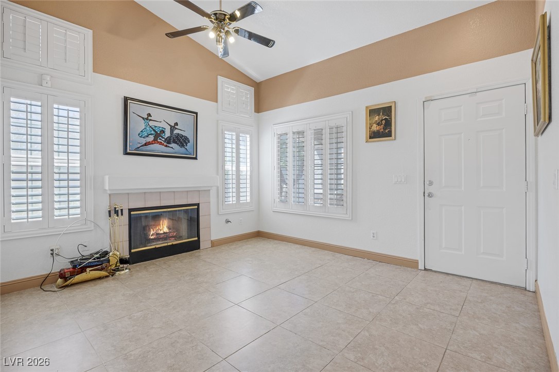 2427 Worchester Road Henderson, NV 89074 - Photo 9 of 35 Unfurnished living room featuring a fireplace, a ceiling fan, light tile patterned flooring, and high vaulted ceiling