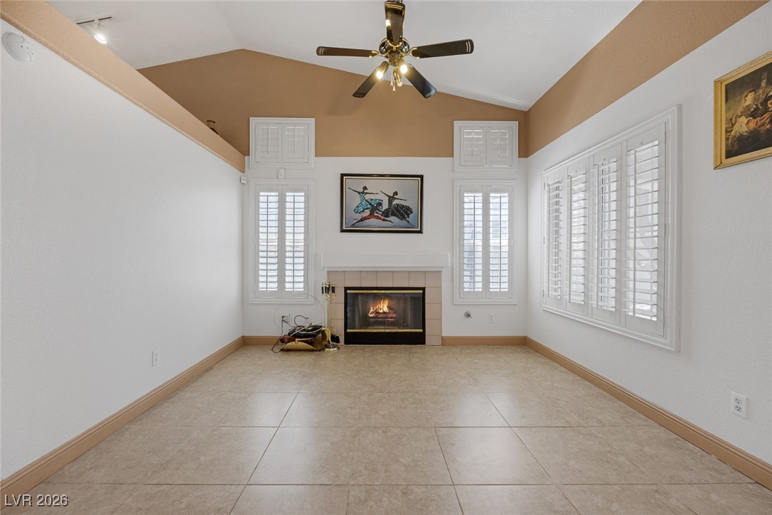 2427 Worchester Road Henderson, NV 89074 - Photo 10 of 35 Unfurnished living room featuring vaulted ceiling, a fireplace, healthy amount of natural light, ceiling fan, and light tile patterned flooring