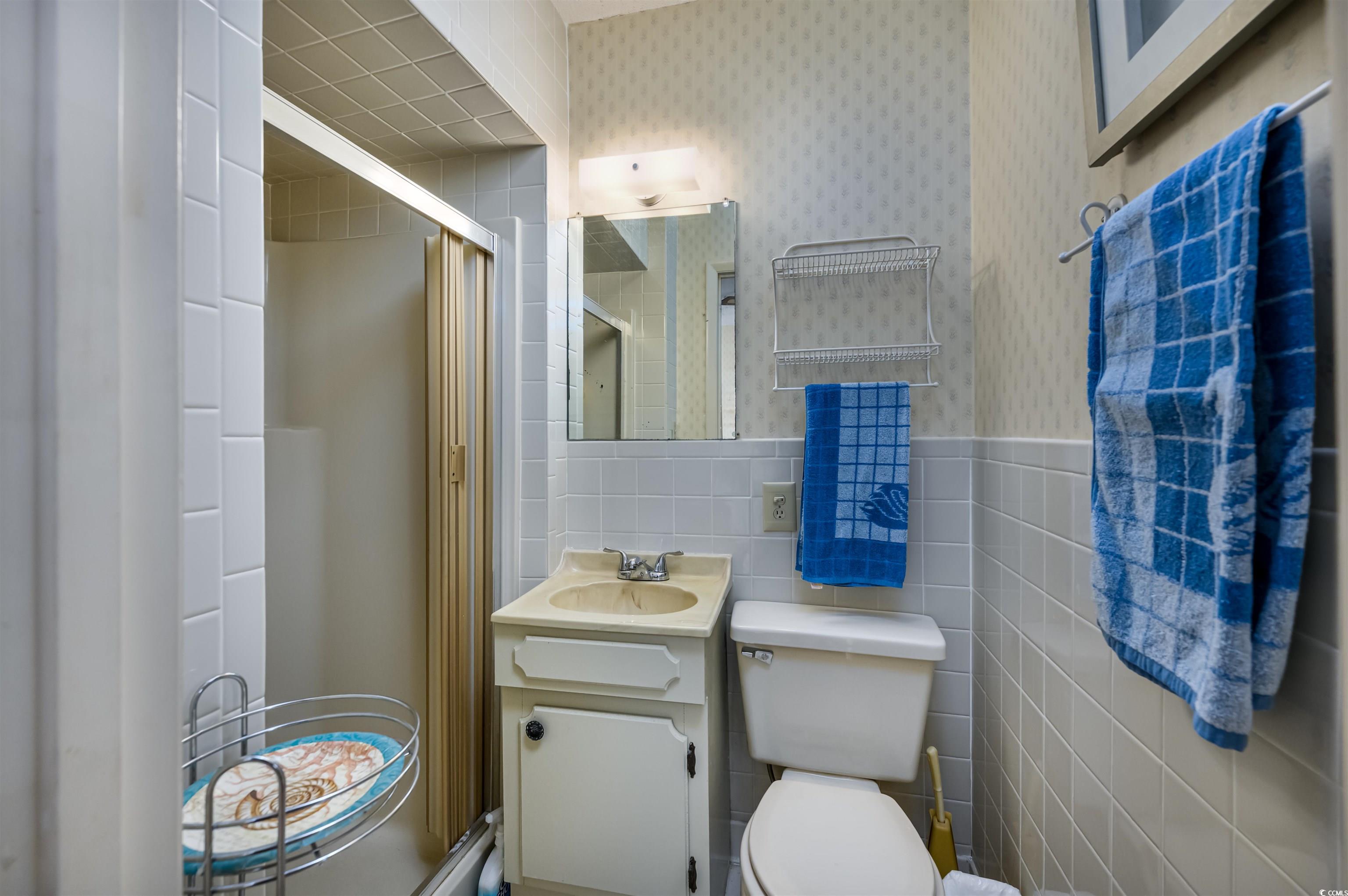 10200 Lakeshore Drive, Unit 16 Myrtle Beach, SC 29572 - Photo 29 of 36 Full bathroom featuring tile walls, toilet, a stall shower, vanity, and wallpapered walls