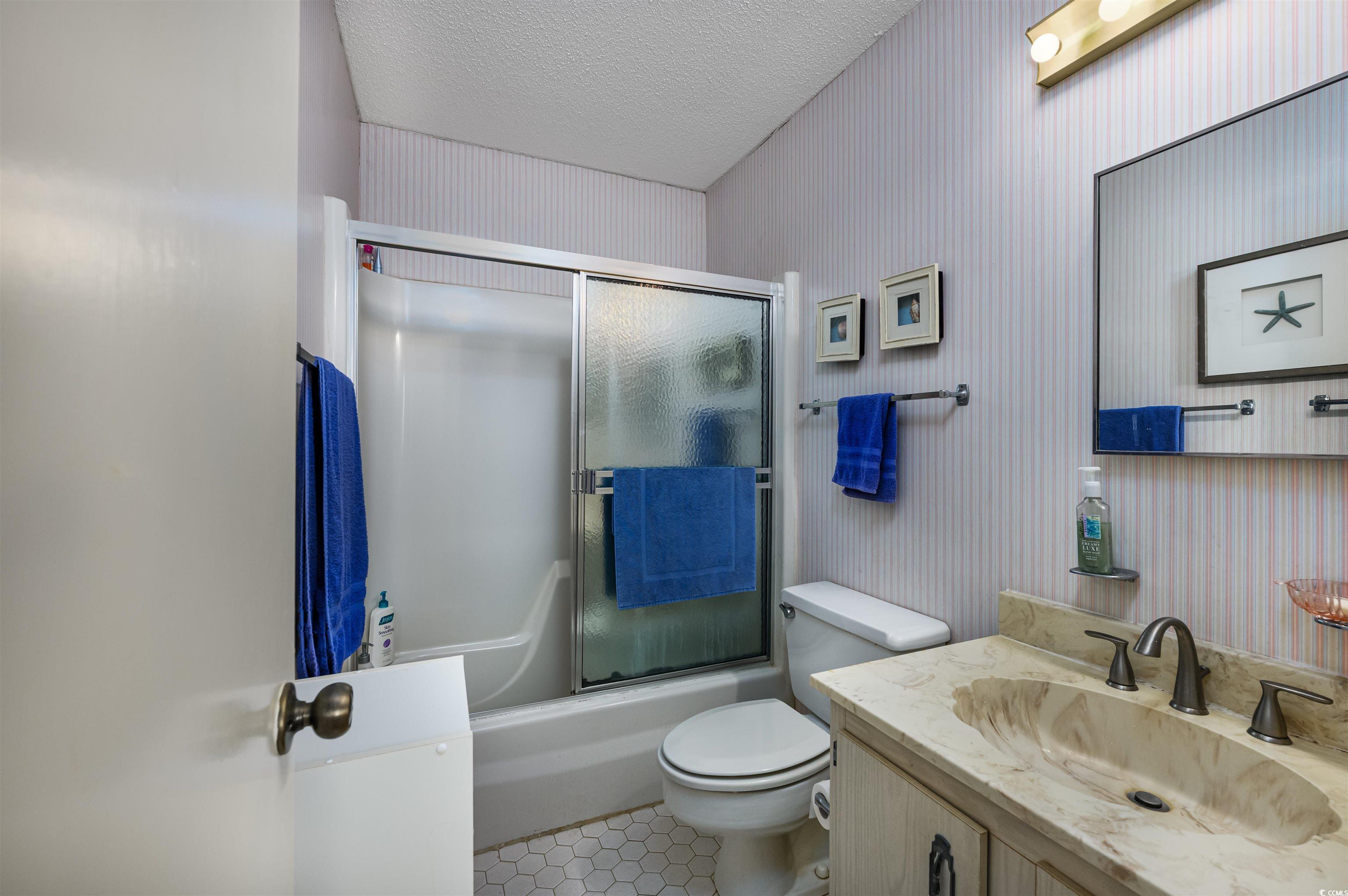 10200 Lakeshore Drive, Unit 16 Myrtle Beach, SC 29572 - Photo 32 of 36 Full bathroom with a textured ceiling, toilet, shower / bath combination with glass door, vanity, and tile patterned floors