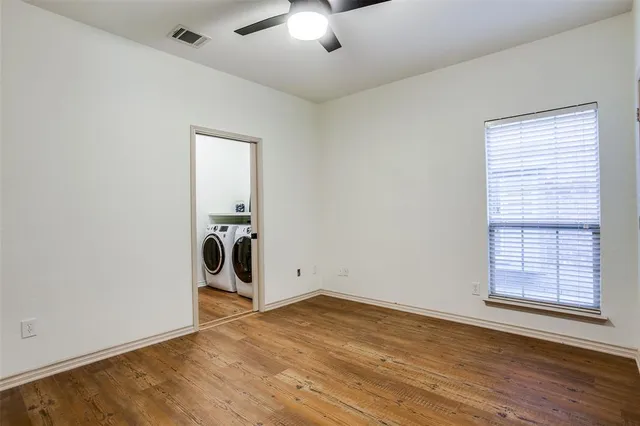 an empty room with wooden floor cabinet and windows