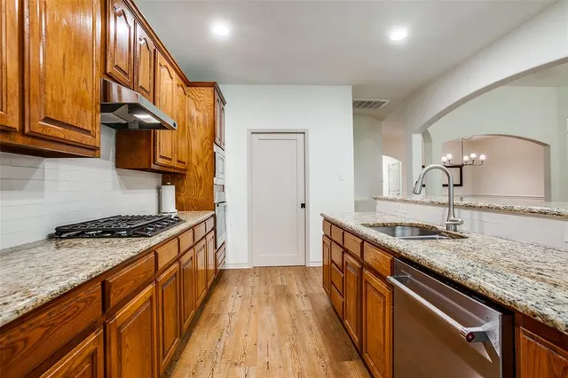 a kitchen with granite countertop stainless steel appliances a sink stove top oven and cabinets