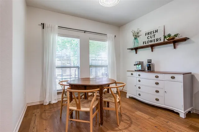 a dining room with wooden floor and windows