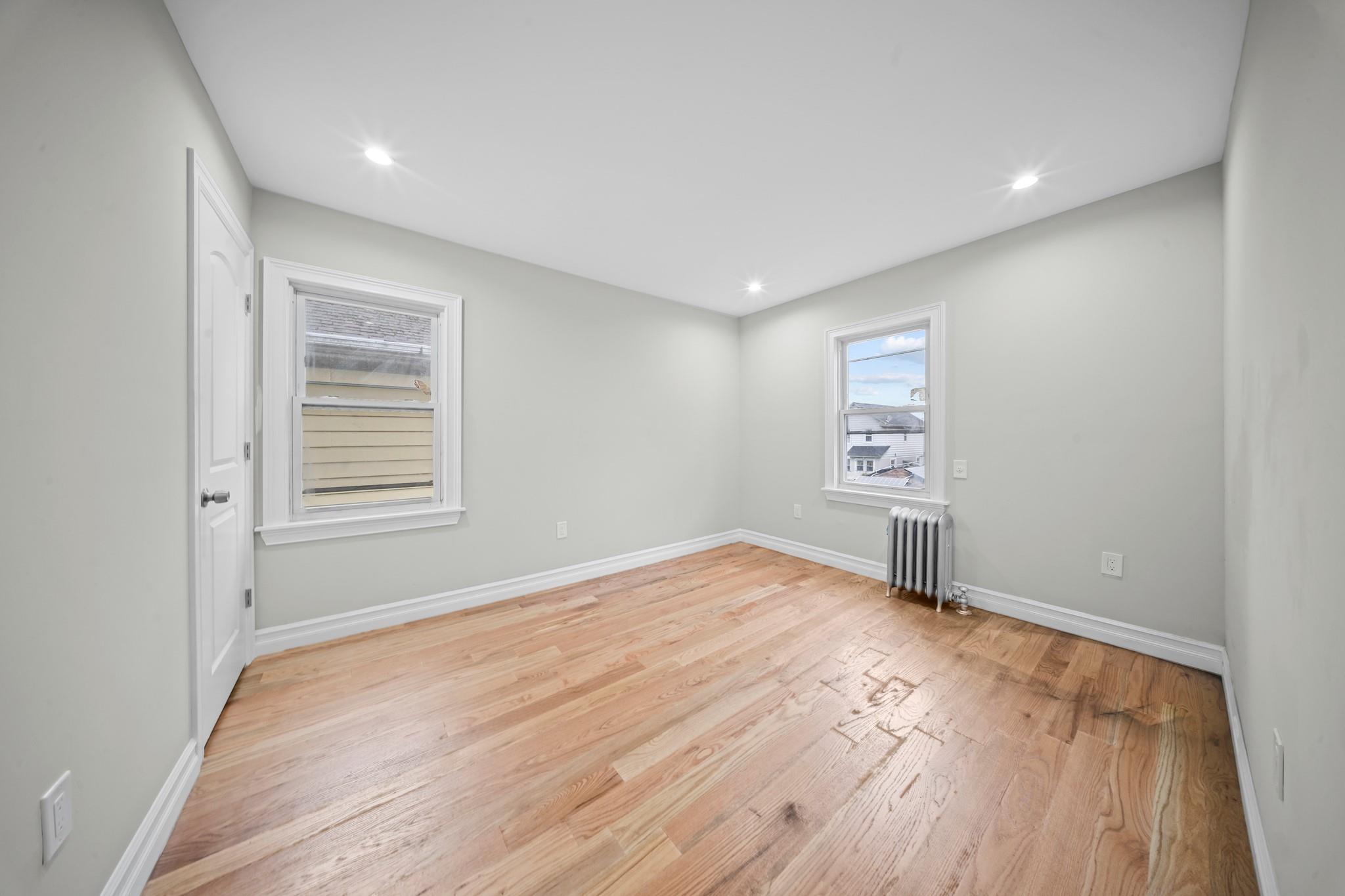 110-28 213th Street Queens, NY 11429 - Photo 11 of 22 Unfurnished room with radiator, light wood-style floors, baseboards, and recessed lighting