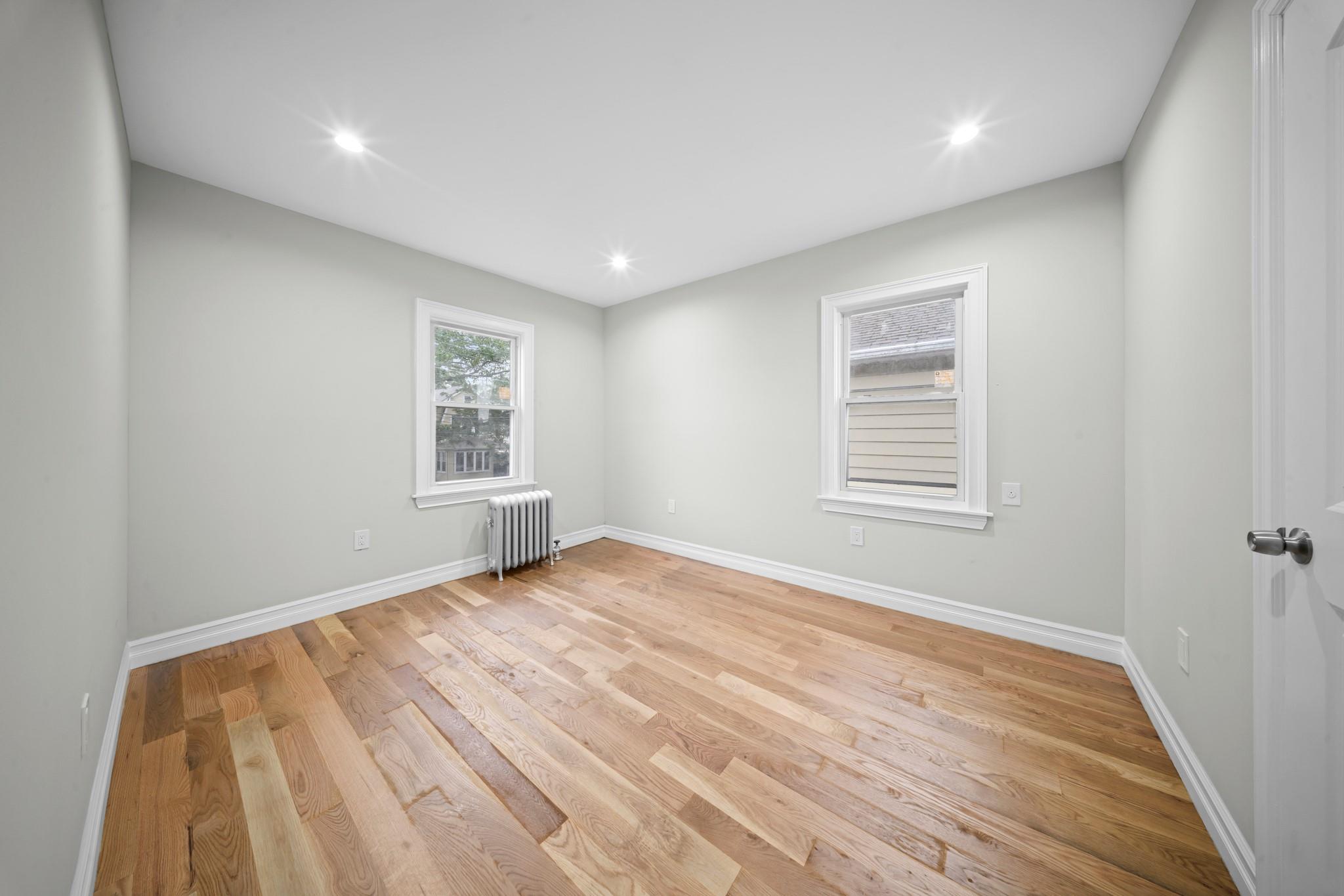 110-28 213th Street Queens, NY 11429 - Photo 13 of 22 Spare room with radiator heating unit, light wood-style flooring, baseboards, and recessed lighting