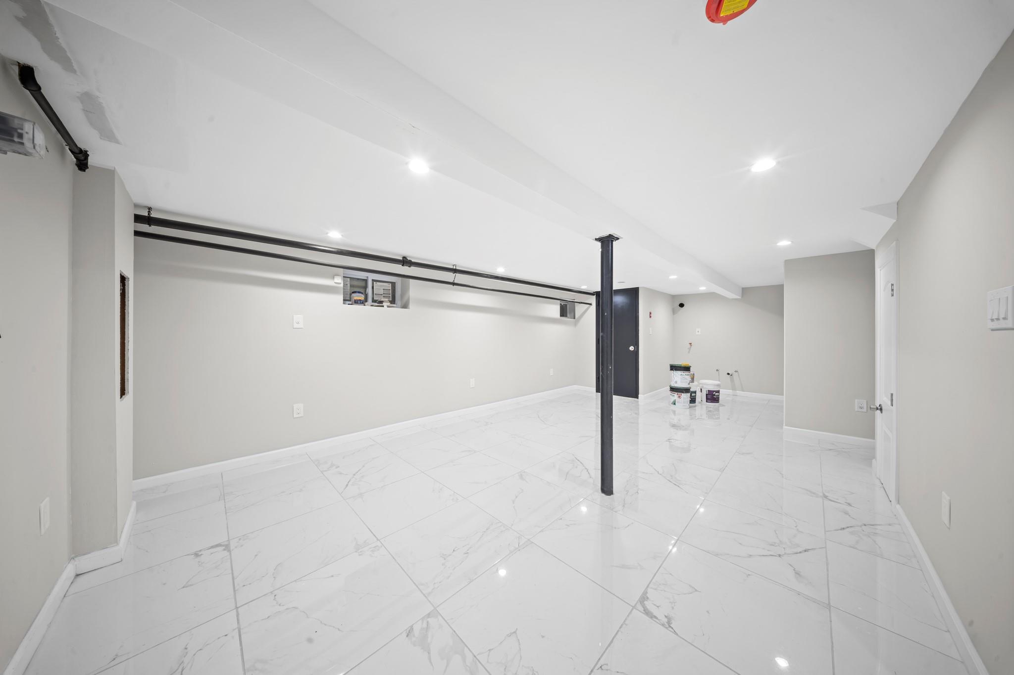 110-28 213th Street Queens, NY 11429 - Photo 15 of 22 Finished basement with light marble finish floors, recessed lighting, and baseboards