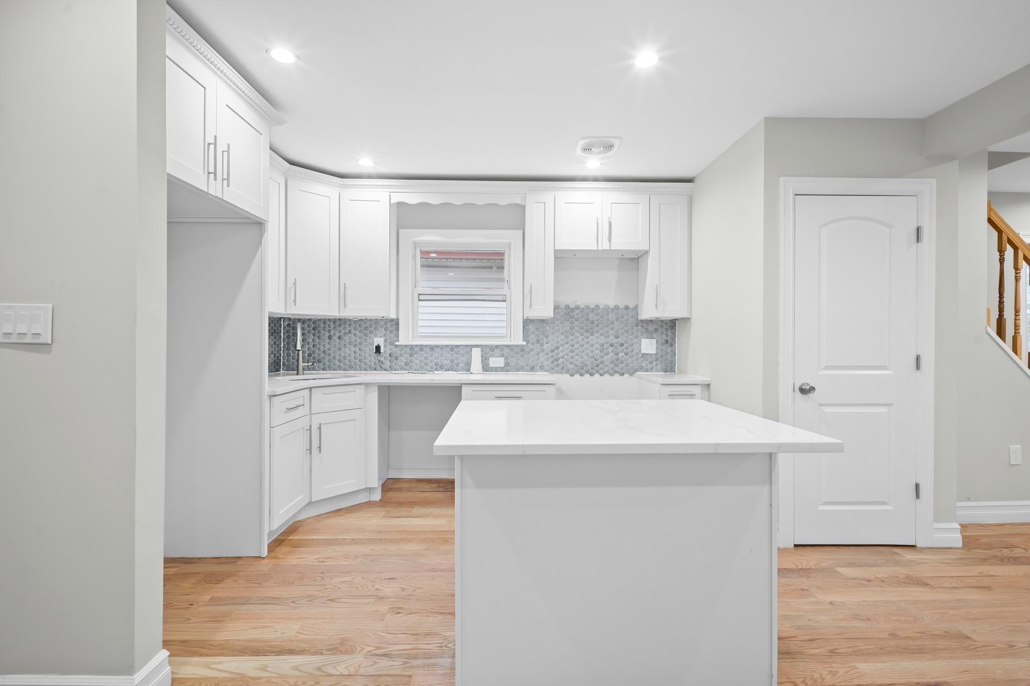 110-28 213th Street Queens, NY 11429 - Photo 2 of 22 Kitchen featuring light wood-style floors, decorative backsplash, white cabinetry, and recessed lighting
