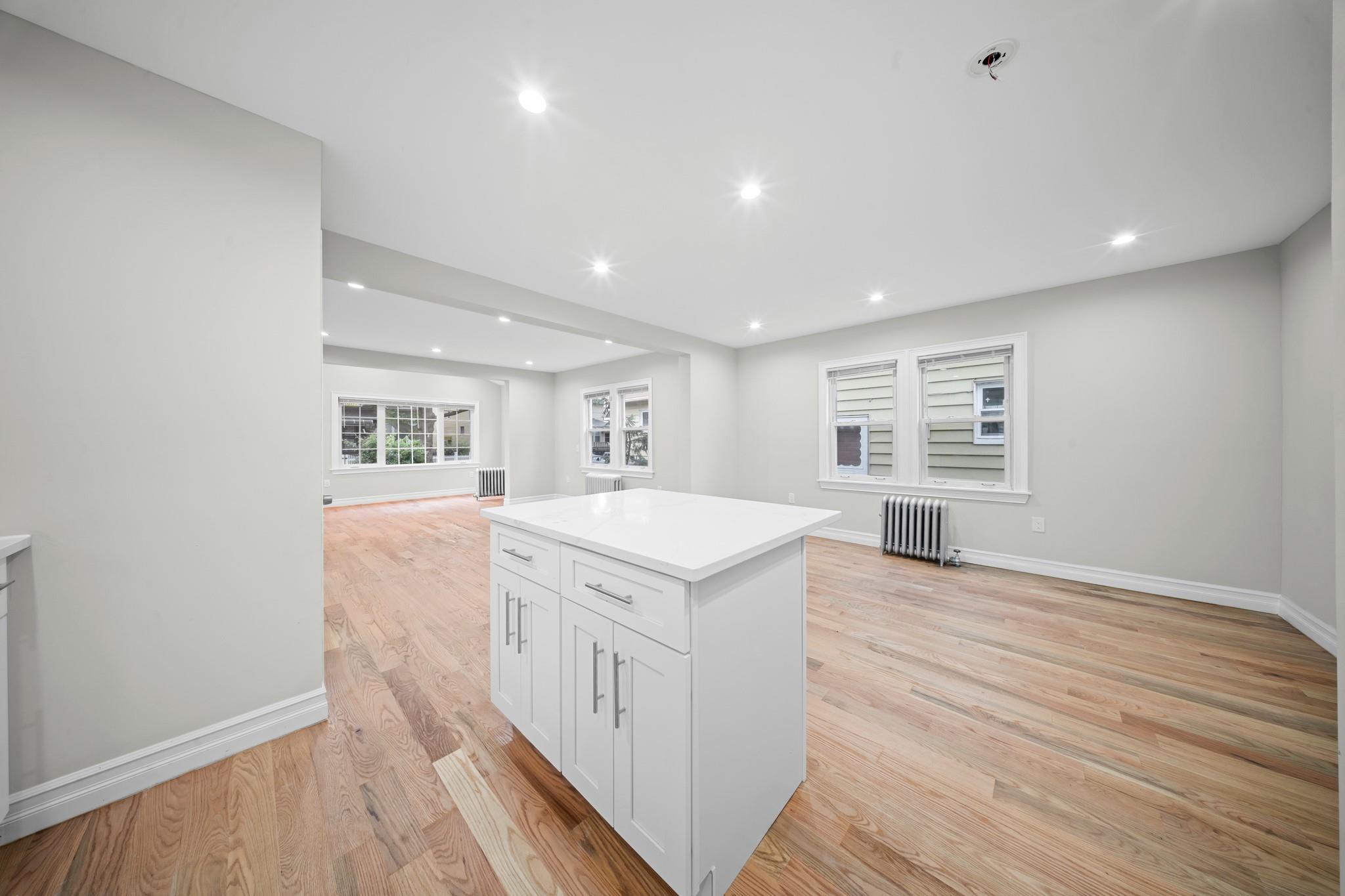 110-28 213th Street Queens, NY 11429 - Photo 22 of 22 Kitchen with radiator, open floor plan, a center island, white cabinetry, and light wood finished floors