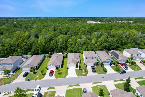 an aerial view of residential houses with outdoor space and lake view in back