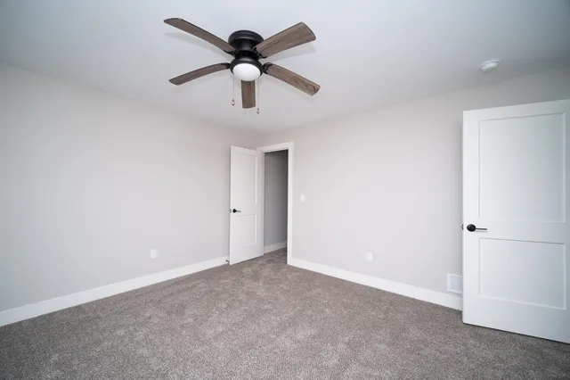 an empty room with a hallway and a ceiling fan