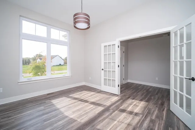 an empty room with wooden floor and windows