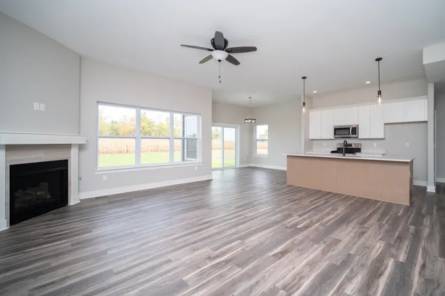 a view of an empty room with wooden floor and a kitchen