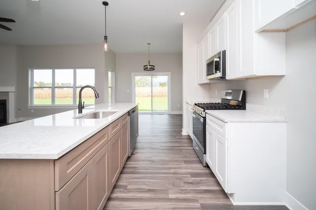 a kitchen with kitchen island granite countertop a sink a stove top oven a counter space and cabinets