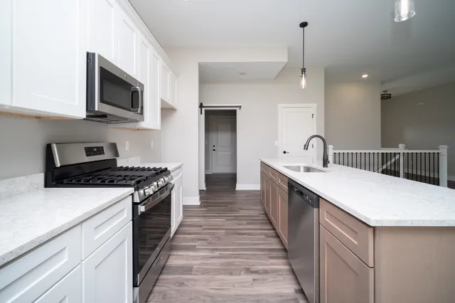 a large kitchen with a stove top oven a sink a counter space and cabinets