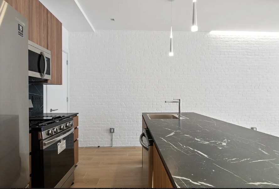 160 Franklin Street, Unit 5 Manhattan, NY 10013 - Photo 7 of 12 a kitchen with stainless steel appliances wooden floor dining table and chairs