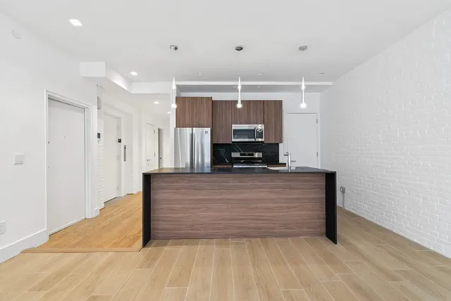 a kitchen with stainless steel appliances wooden floor dining table and chairs