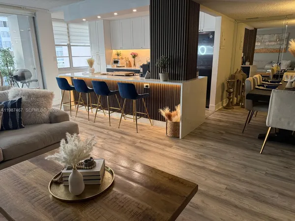 a living room with furniture a wooden floor and kitchen view