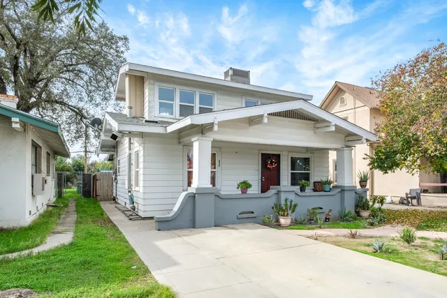 a front view of a house with a yard and potted plants