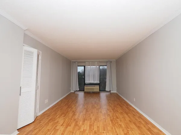 a view of an empty room with a window and wooden floor
