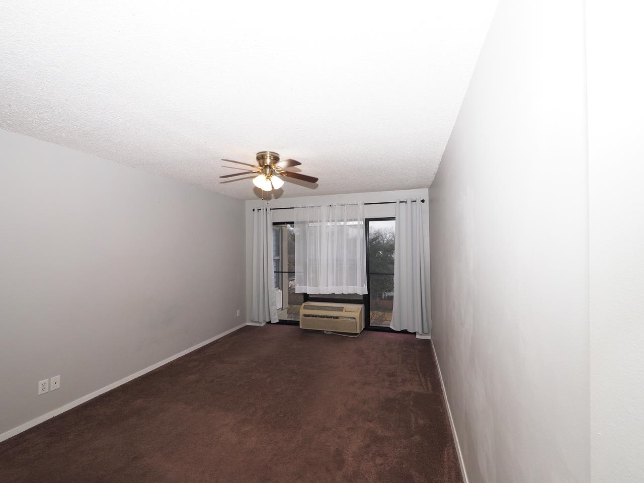232 South Highland Street, Unit 505 Memphis, TN 38111 - Photo 6 of 7 Unfurnished living room featuring dark colored carpet, ceiling fan, and a wall unit AC