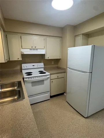 a kitchen with a refrigerator sink stove and cabinets