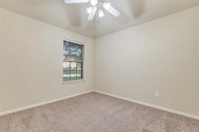 an empty room with a chandelier fan and windows