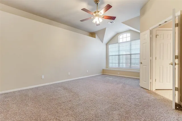 an empty room with windows and ceiling fan