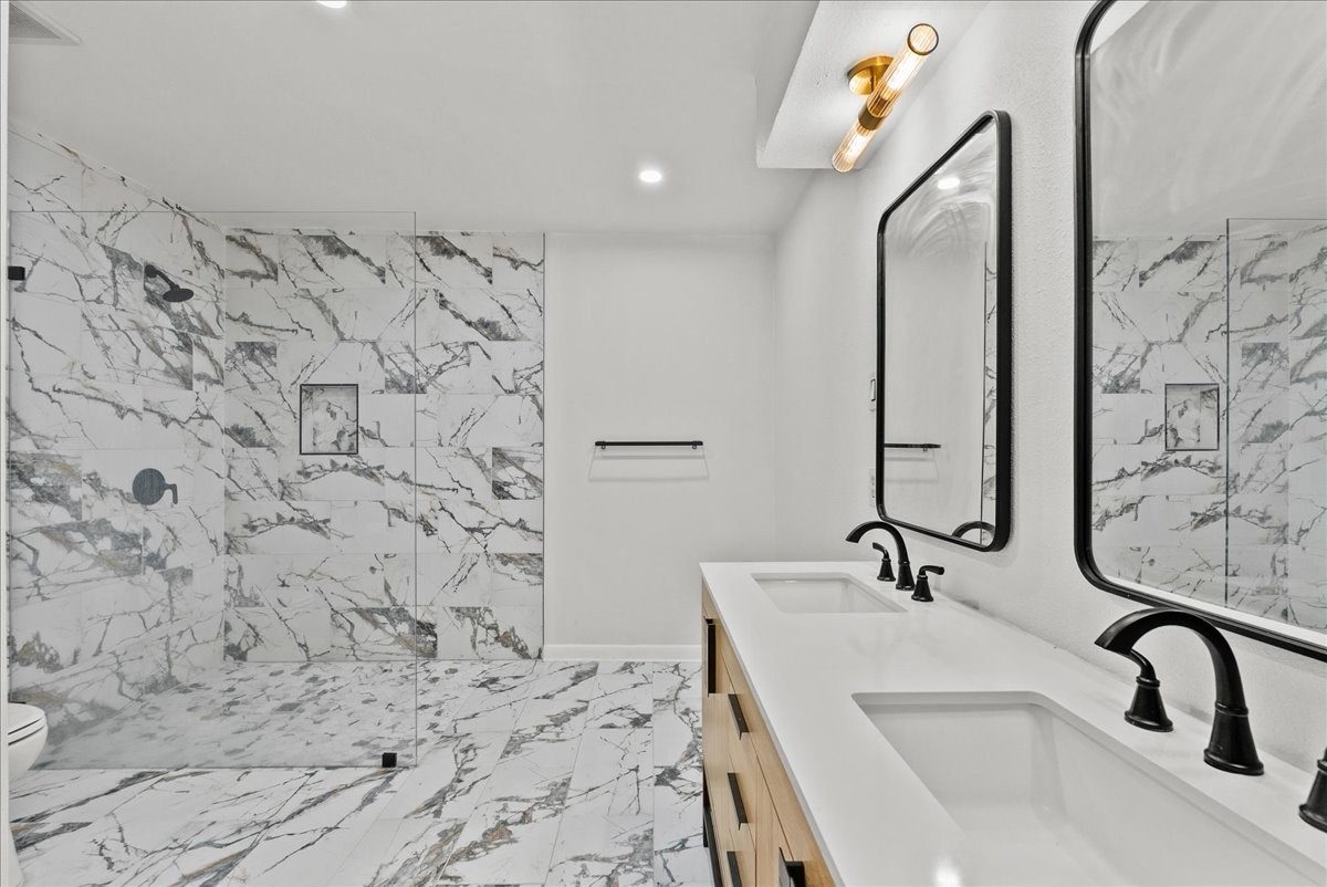 5762 Birdwood Road Houston, TX 77096 - Photo 27 of 50 THIS LUXURY PRIMARY BATH WITH THE LARGE FRAMELESS WALK IN SHOWER ALSO HAS WALL OF BUILT IN CABINETS AND DRAWERS ON THE OPPOSITE WALL.