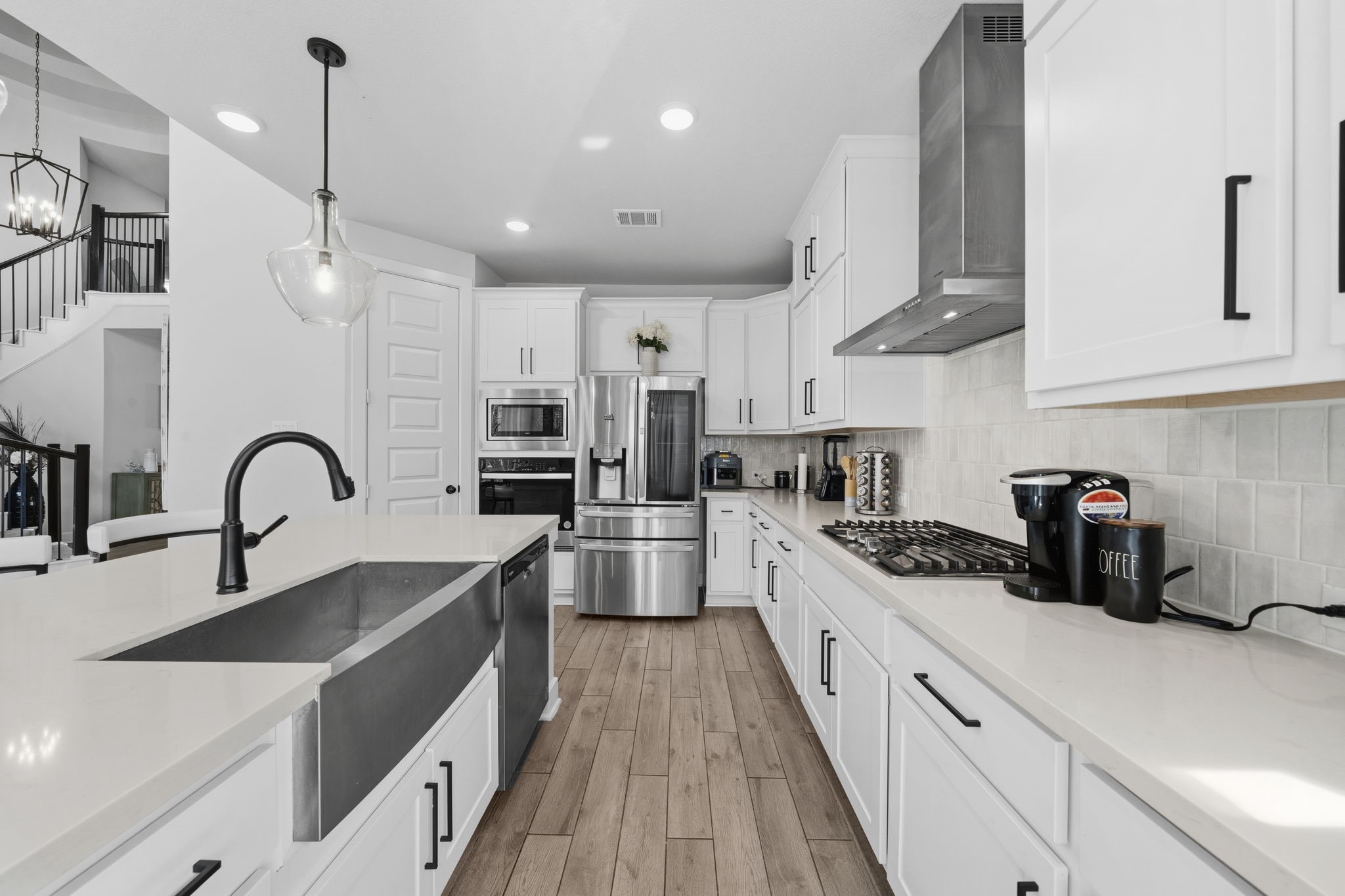 511 Carina Gaze Drive Conroe, TX 77318 - Photo 11 of 45 This modern kitchen features sleek white cabinetry, stainless steel appliances, and a spacious island with a farmhouse sink.