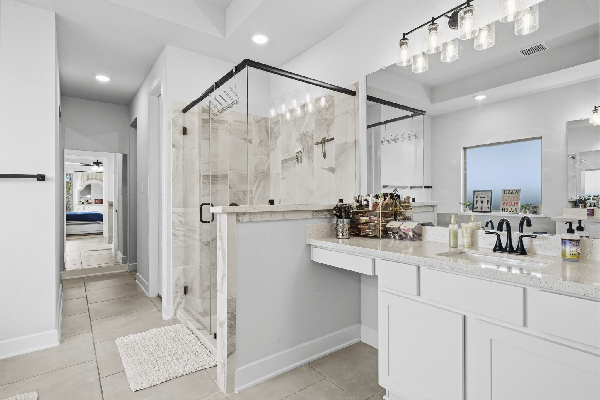 511 Carina Gaze Drive Conroe, TX 77318 - Photo 19 of 45 This bathroom features a spacious layout with a modern glass-enclosed shower, double sinks, and ample counter space. It's well-lit with contemporary fixtures and has a sleek, neutral tile floor. The design offers a clean and inviting atmosphere.