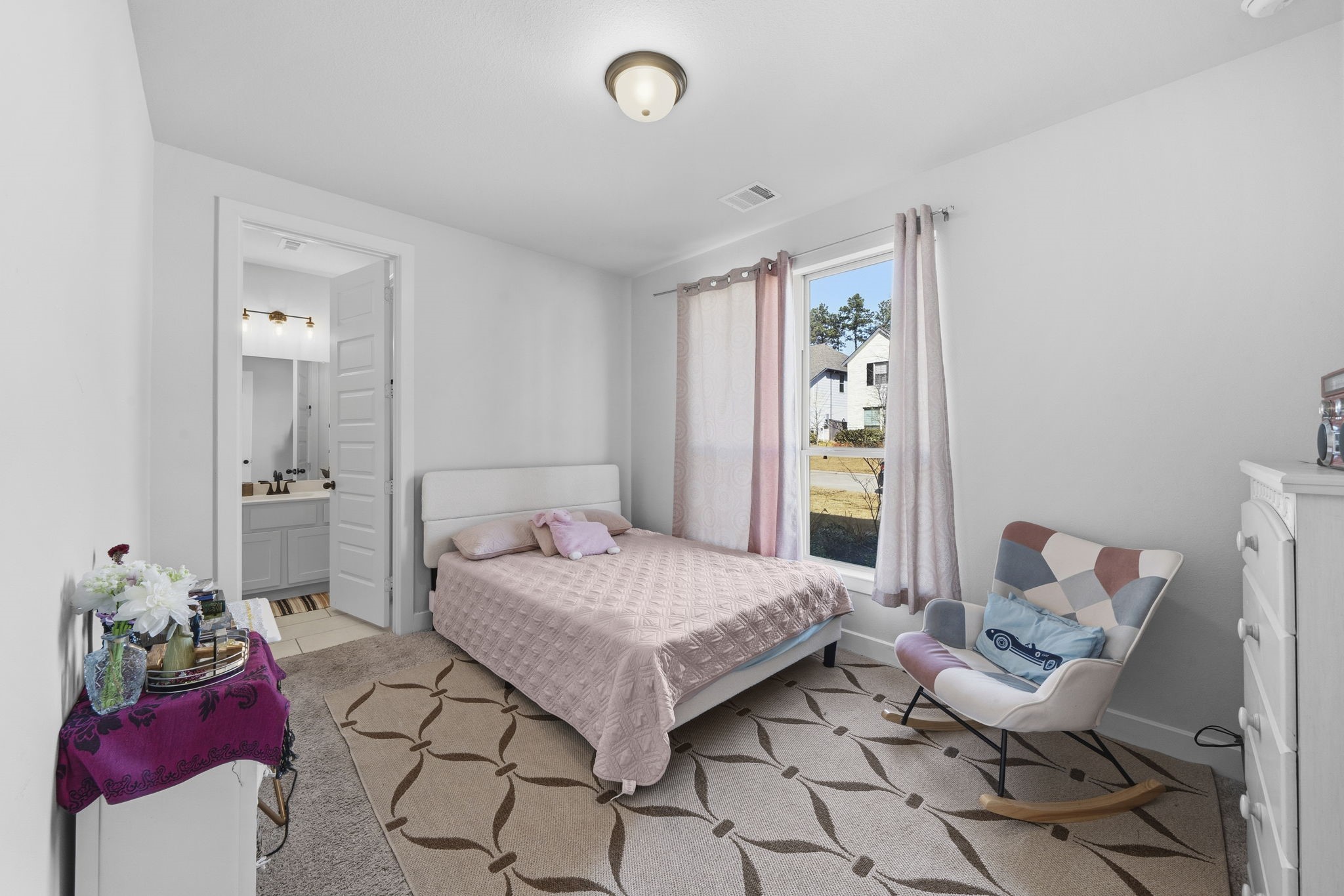 511 Carina Gaze Drive Conroe, TX 77318 - Photo 20 of 45 Bright and cozy bedroom with a large window, providing ample natural light. Features a comfortable bed, a stylish armchair, and access to an en-suite bathroom.