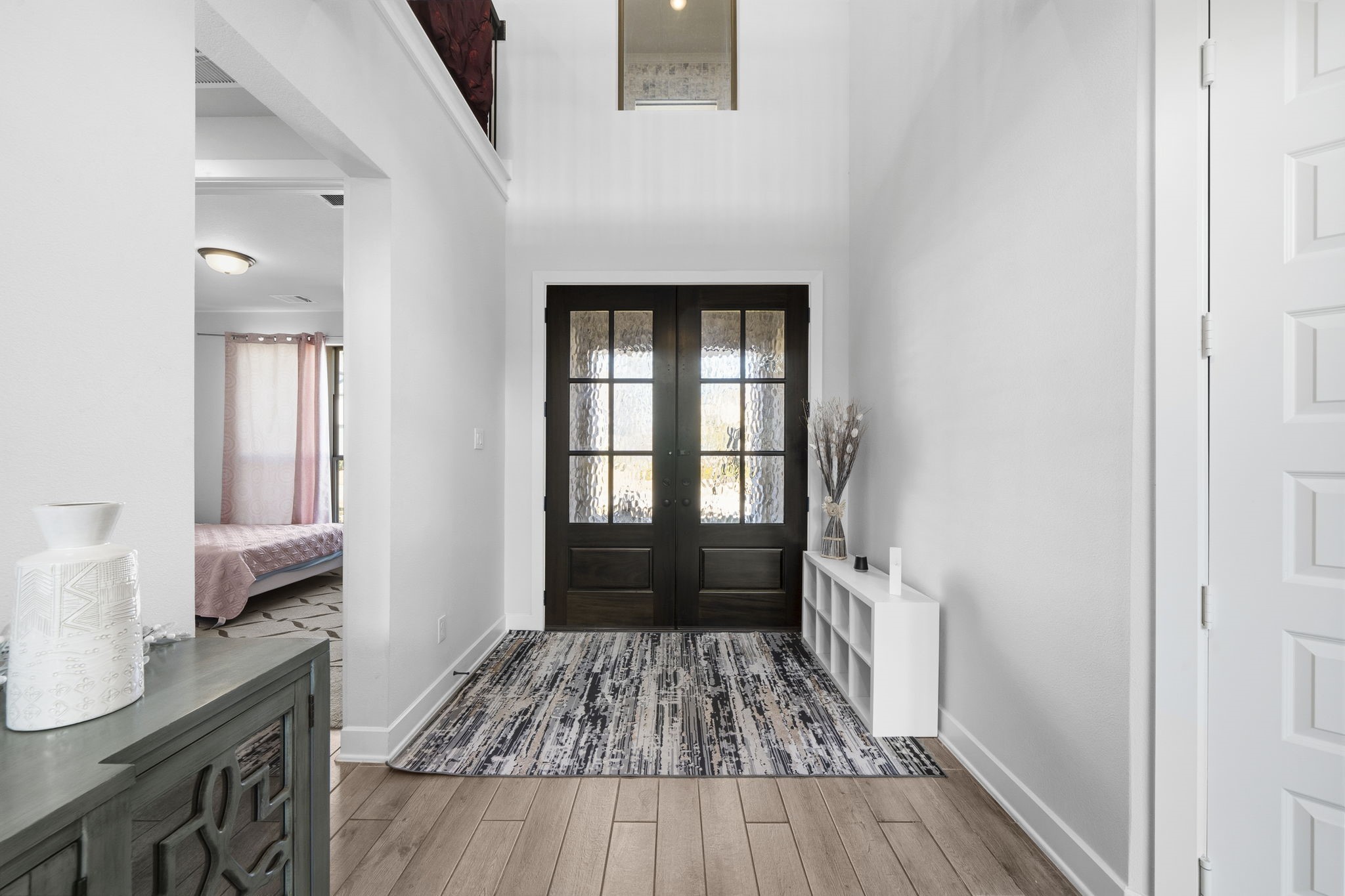 511 Carina Gaze Drive Conroe, TX 77318 - Photo 2 of 45 Bright and inviting entrance hall with high ceilings, featuring a modern glass-paneled double door, light wood flooring, and a stylish rug.