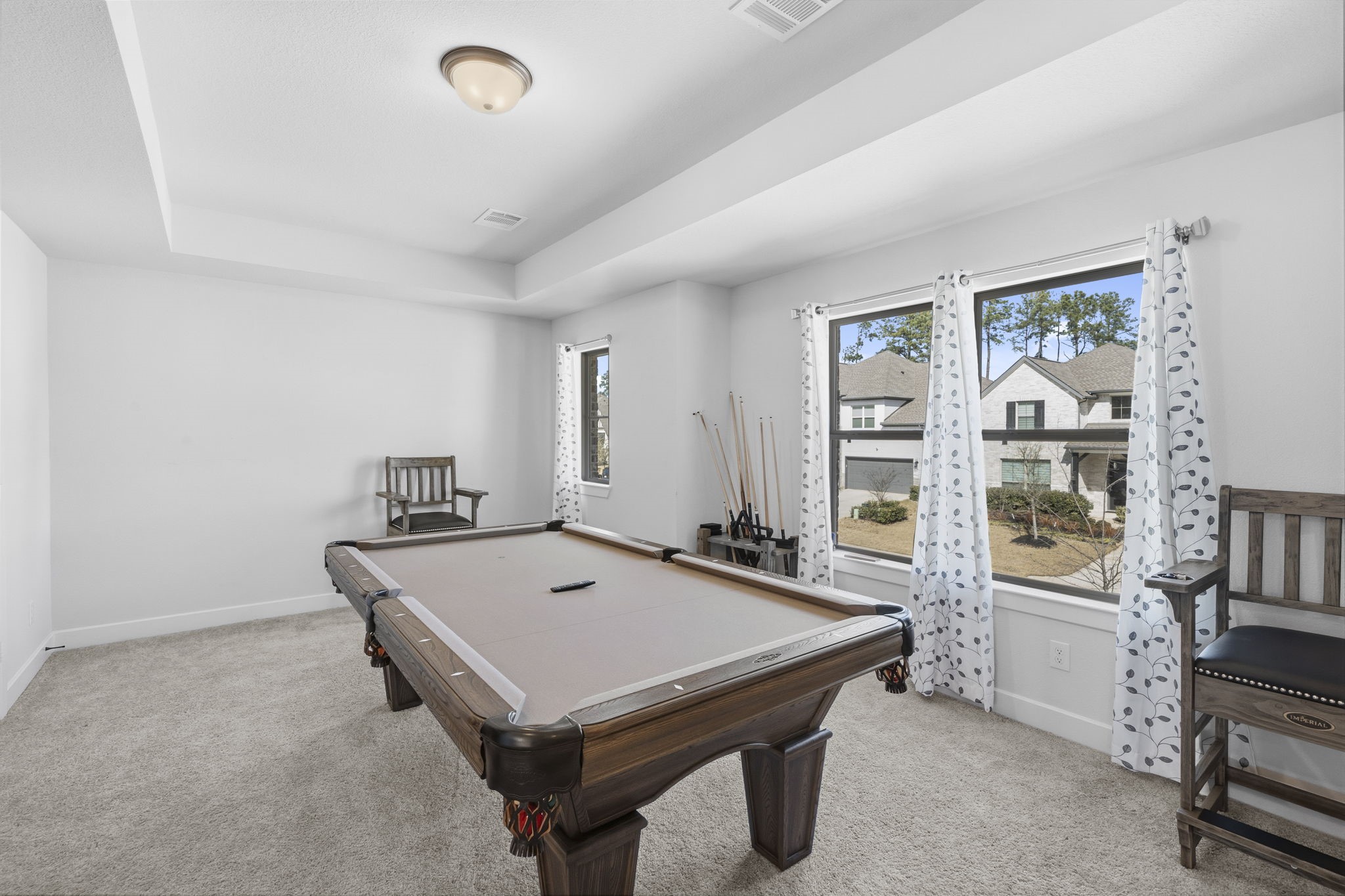 511 Carina Gaze Drive Conroe, TX 77318 - Photo 23 of 45 This room features a pool table with ample space for entertainment. Natural light pours in through large windows with a view of the neighborhood. It has neutral carpeting and a simple, elegant design.