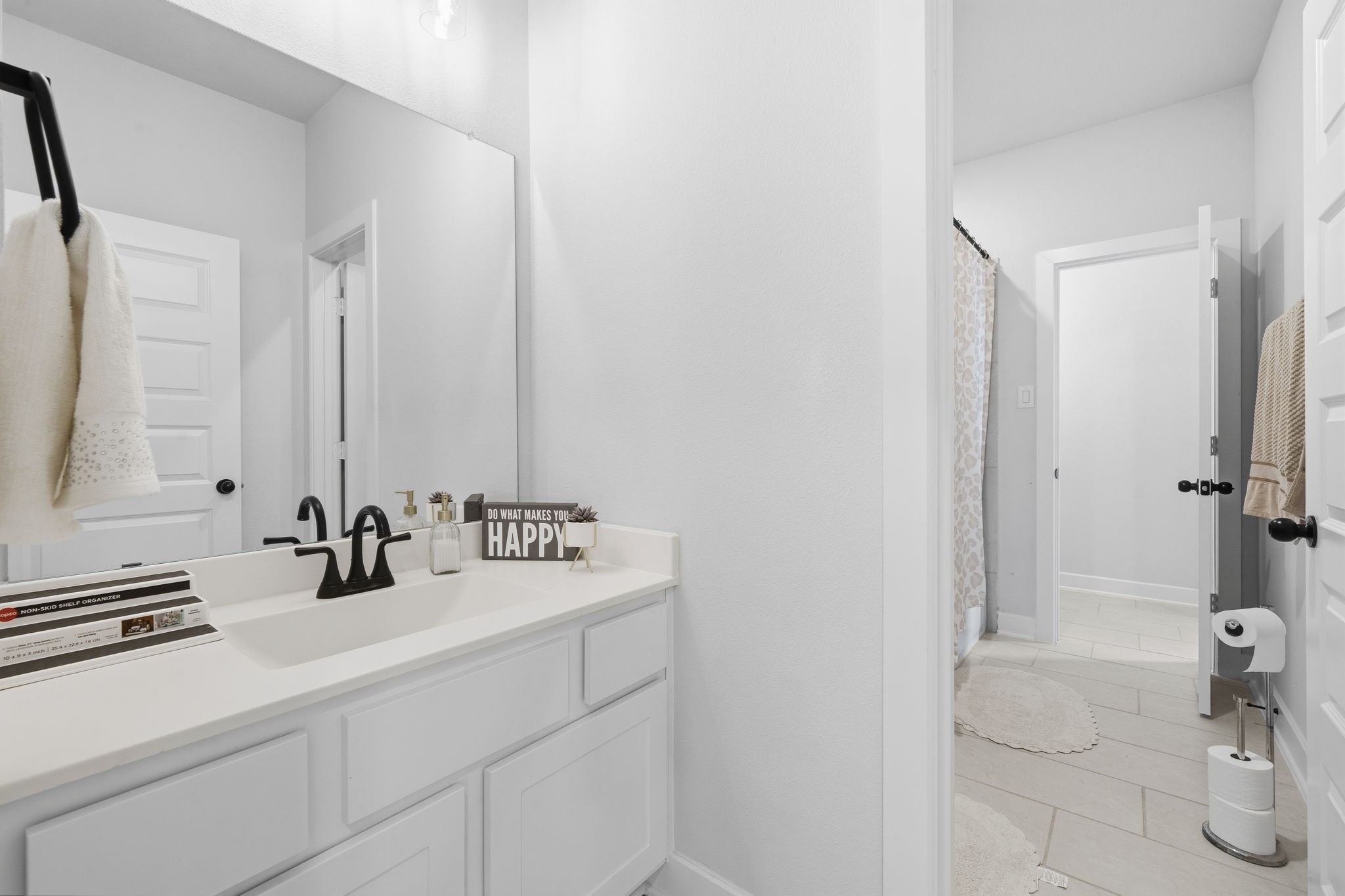 511 Carina Gaze Drive Conroe, TX 77318 - Photo 28 of 45 Bright, modern bathroom with a white vanity, sleek black fixtures, and a large mirror.