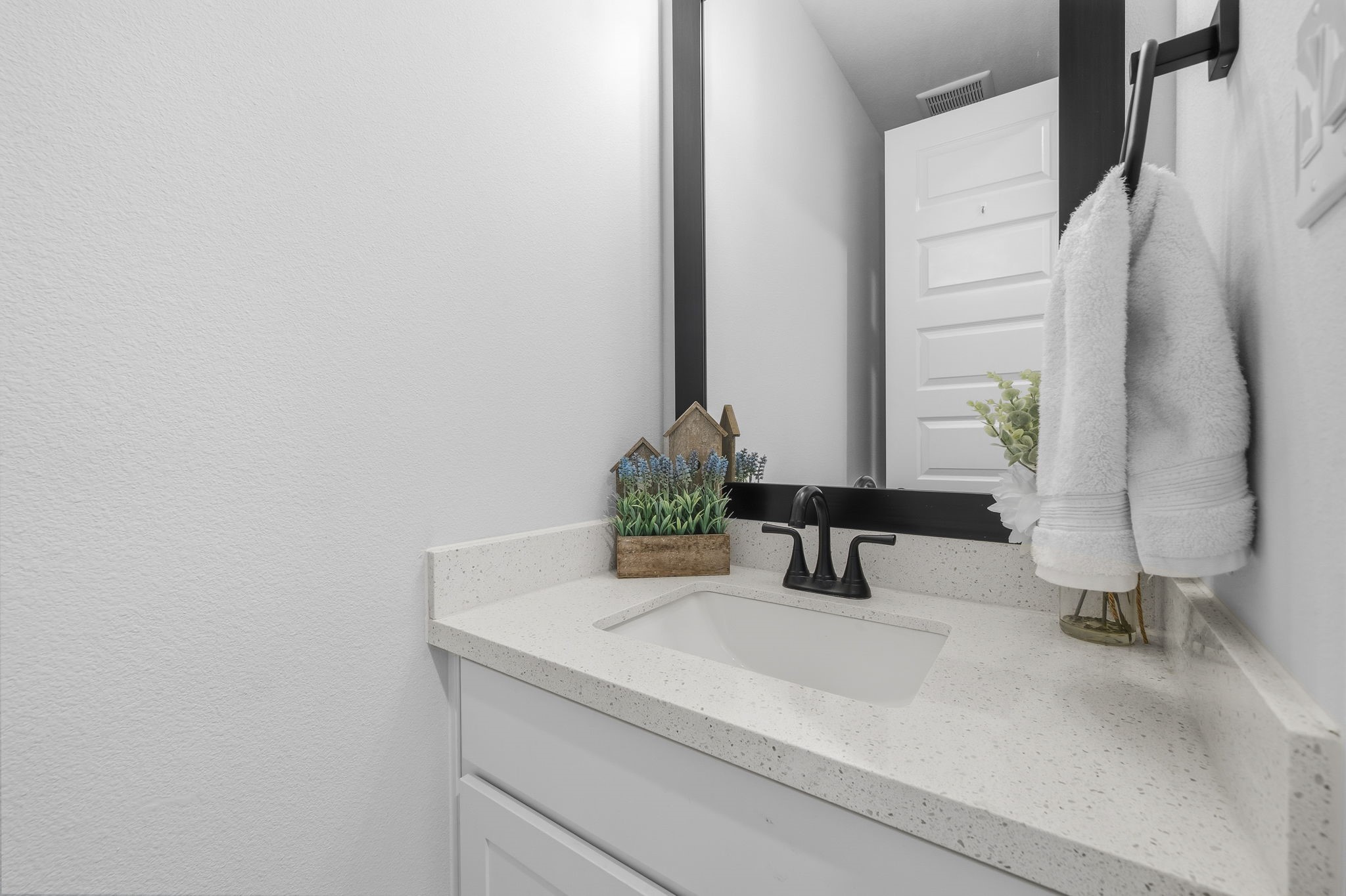 511 Carina Gaze Drive Conroe, TX 77318 - Photo 32 of 45 This half bathroom features a modern design with a sleek white countertop, undermount sink, and black faucet. It includes a large mirror.