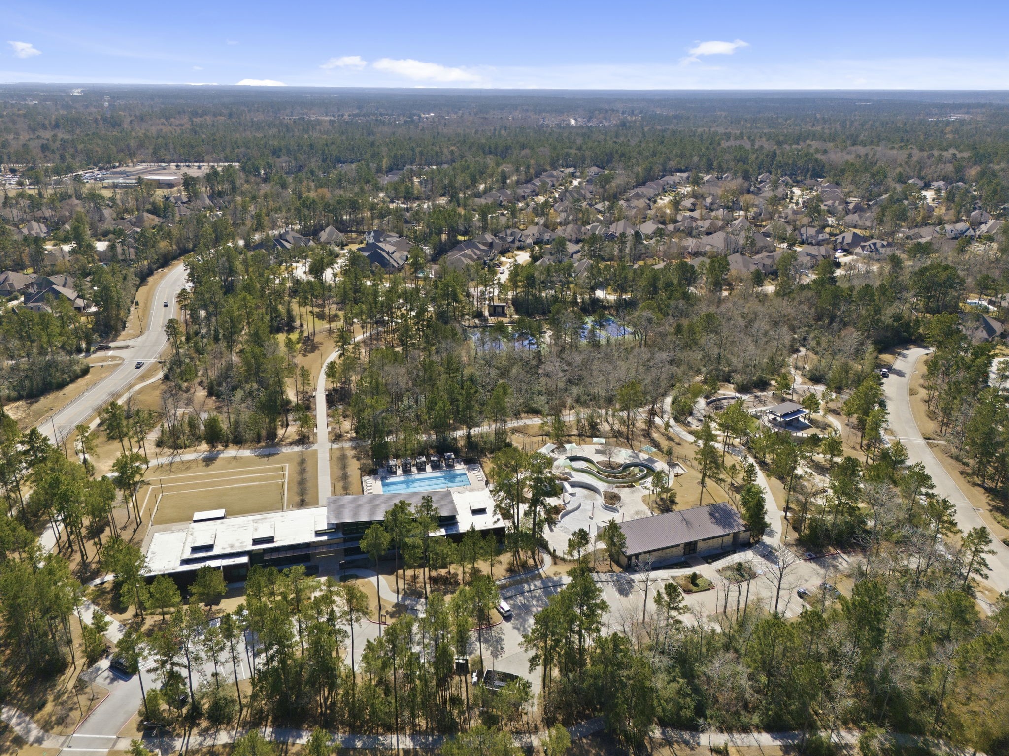 511 Carina Gaze Drive Conroe, TX 77318 - Photo 40 of 45 This photo showcases a serene residential neighborhood in The Woodlands Hills surrounded by lush greenery. It features winding roads, spacious homes, and community amenities like a swimming pool and sports fields, offering a peaceful suburban lifestyle.