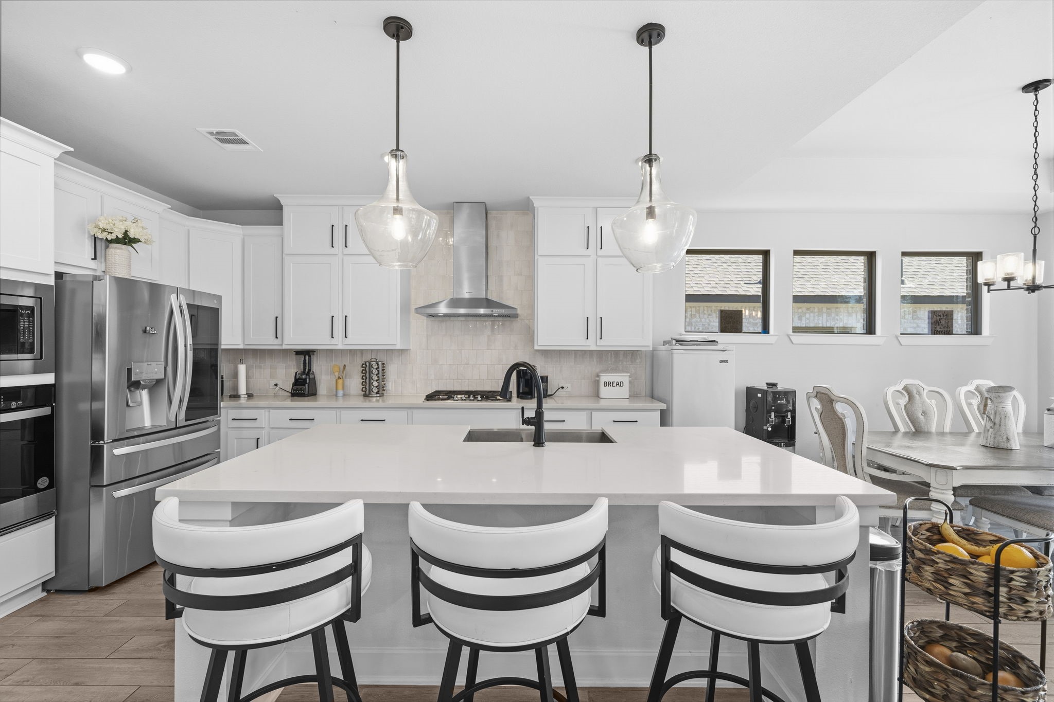 511 Carina Gaze Drive Conroe, TX 77318 - Photo 4 of 45 This modern kitchen features a spacious island with seating for three, sleek stainless steel appliances, and elegant pendant lighting. White cabinetry and ample natural light create a bright and inviting atmosphere, seamlessly connecting to the dining area.