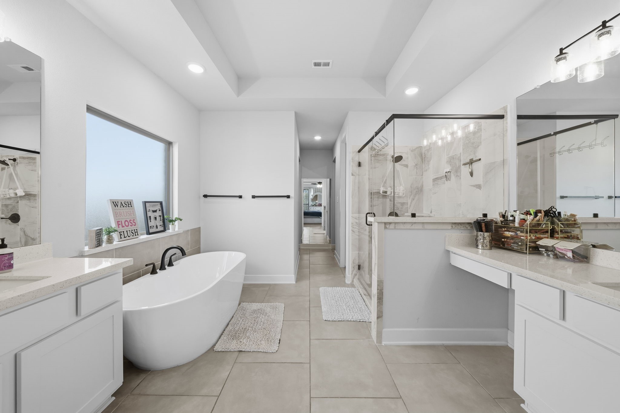511 Carina Gaze Drive Conroe, TX 77318 - Photo 5 of 45 This photo showcases a spacious, modern bathroom with a freestanding tub, large walk-in shower, and dual vanities. The design is sleek, featuring neutral tones and ample natural light, creating a luxurious and inviting atmosphere.