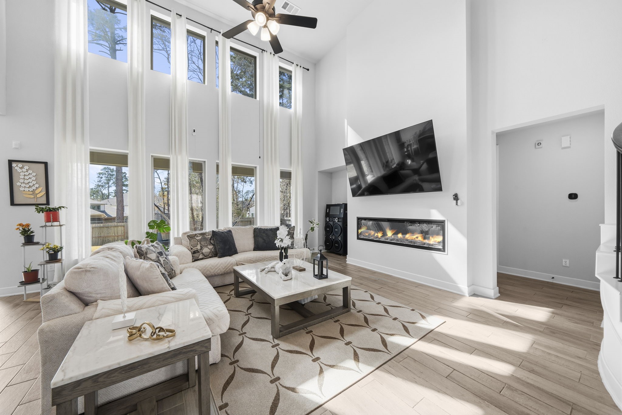 511 Carina Gaze Drive Conroe, TX 77318 - Photo 9 of 45 This spacious living room features soaring ceilings with tall windows that flood the space with natural light. It has a modern design with a sleek fireplace.